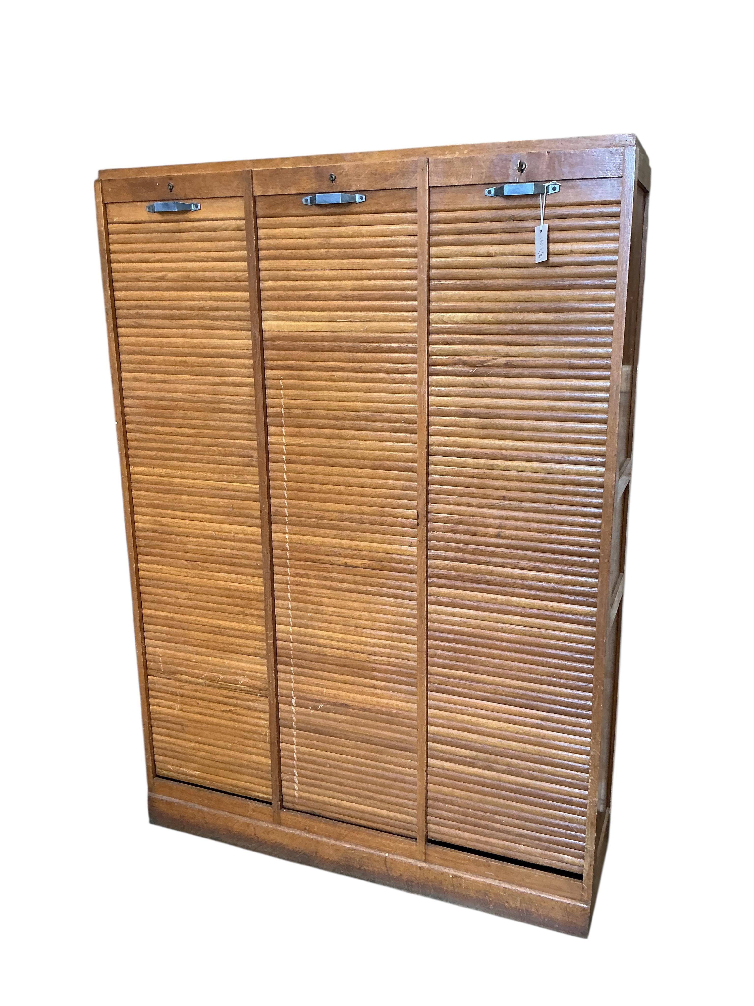 A mid 20th century oak triple tambour filing cabinet, width 126cm, depth 38cm, height 180cm